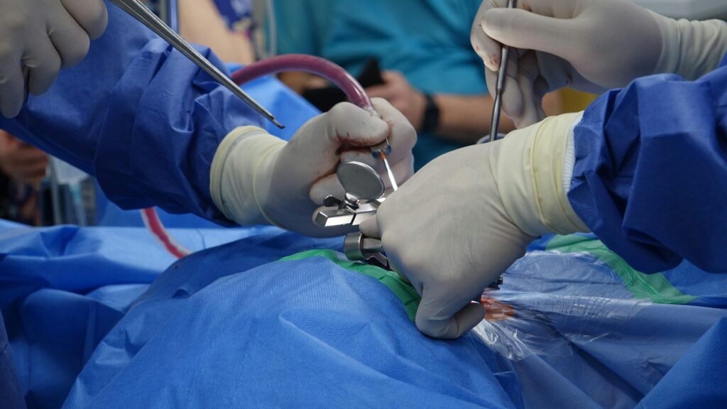 Surgeons in sterile gloves perform a spinal operation in a modern operating room, focusing on precision and care.